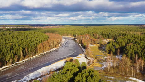 Partly-frozen-River-Gauja-with-lush-green-forests-surrounding,-Valmiera,-Latvia