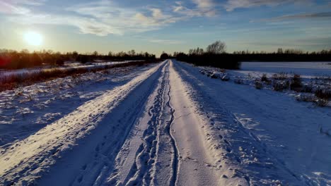 Un-Camino-Cubierto-De-Nieve-Se-Extiende-A-Lo-Lejos,-Con-Un-Cielo-Azul-Claro-Y-Largas-Sombras-Proyectadas-Por-El-Sol-Poniente