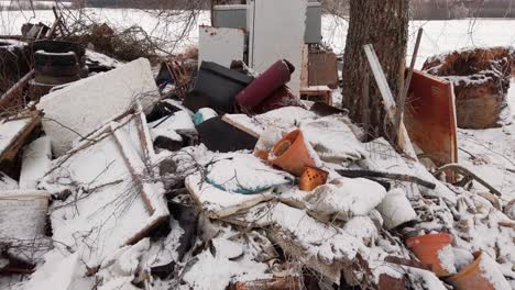 Pile-of-household-garbage-in-countryside-yard-near-bare-tree,-winter-environment