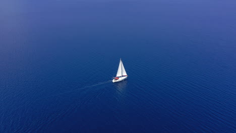 Aerial:-One-sailboat-out-in-the-open-blue-Aegean-sea-on-a-clear-summer-day