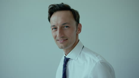 Young-dark-haired-man-fixes-tie-and-smiles,-close-eye-contact-shot