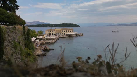 Static-establishing-shot-of-old-Greek-hotel-at-edge-of-rocky-coastline-in-Corfu-Greece