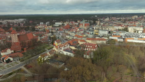 Captivating-aerial-perspective-of-Olsztyn's-city-center,-showcasing-the-blend-of-Gothic-architecture-and-modern-urban-landscapes-against-a-dramatic-cloudy-sky-in-northern-Poland