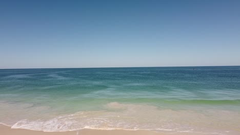 Beautiful-beach-scene,-aerial-rise-up-clip-over-Indian-Ocean-at-Mindarie-Beach-Perth