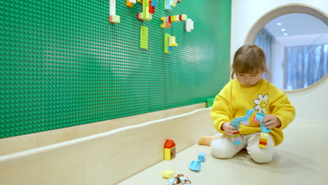 Little-Girl-Playing-With-Colorful-Lego-Blocks-At-Indoor-Playroom---slow-motion-wide
