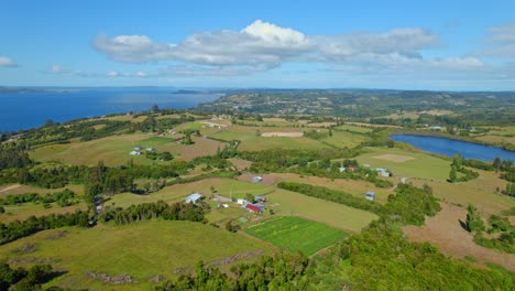 Drone-shot-over-fields-and-rural-nature-on-the-sunny-Lemuy-island,-Chiloe,-Chile