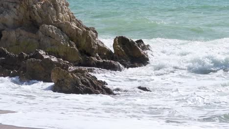 Die-Raue-See-Schlägt-An-Einem-Sonnigen-Tag-Zur-Mittagszeit-Gegen-Die-Felsen,-Wenn-Sie-Das-Ufer-Am-Strand-Erreicht