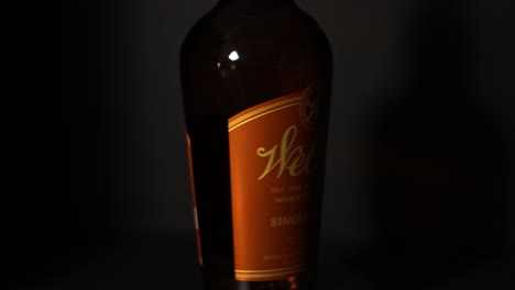 Weller-single-barrel-Kentucky-straight-bourbon-whiskey-rotating-360-degrees-in-the-foreground-with-a-dark-black-background-Frankfort-Kentucky-bourbon-trail-beverage-amber-red-color-STATIC-CLOSE-UP