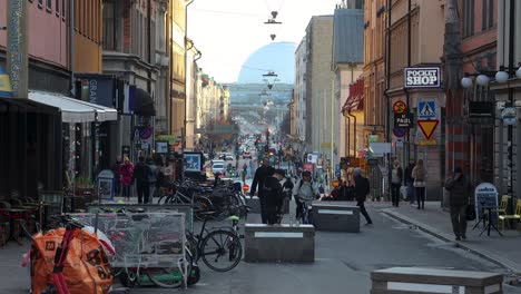 Static-centered-view-of-people-on-street-in-Stockholm,-woman-on-bike