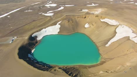 A-4K-drone-captured-cinematic-aerial-footage-of-an-emerald-green-lake-amidst-a-landscape-where-melting-snow-dominates-the-scenery