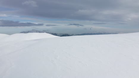 Expansive-snowy-landscape-with-Piatra-Craiului-Mountains-backdrop,-Iezer-Papusa,-Arges