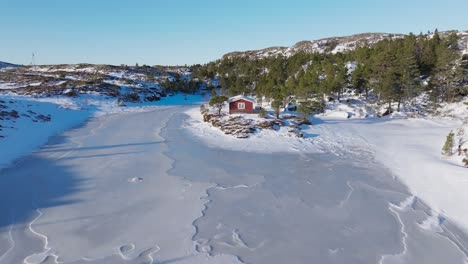 Cabaña-Roja-Tradicional-Junto-Al-Río-Congelado-En-Invierno-En-Bessaker,-Trondelag,-Noruega