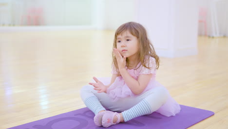 Toddler-Ballerina-Stretches-Legs-in-Empty-Ballet-Studio-in-Playing-Style-Following-Teacher-During-Idividual-Class
