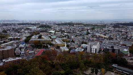 A-dense-cityscape-with-buildings,-trees,-and-cloudy-skies,-daylight,-aerial-view