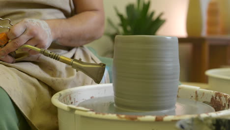 Male-hands-using-propane-torch-glazing-clay-pottery-vase-in-studio-workshop