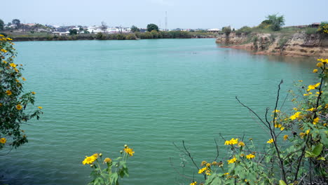 A-natural-dam-or-reservoir-lake-near-Jos,-Nigeria-and-wildflowers-along-the-shoreline