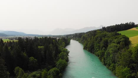Aerial-of-a-river-surrounded-by-forest-and-hills