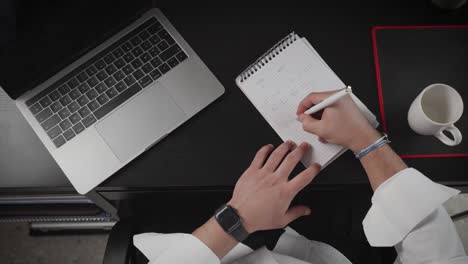 overhead-shot-of-a-person-working-and-taking-notes-at-a-desk