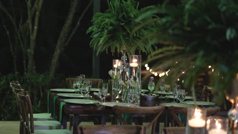 Elegante-Diseño-De-Mesa-De-Banquete-En-Una-Boda,-Con-Cristalería,-Platos,-Centros-De-Mesa-Con-Helechos-Y-Flores