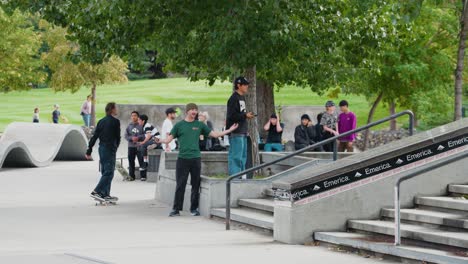 A-Group-of-young-teenage-onlookers-watch-as-skaters-do-tricks-at-a-skate-park