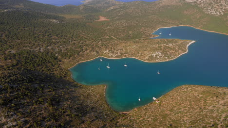 Aerial:-Panoramic-shot-of-planitis-bay-of-the-island-of-Kira-Panagia-in-Sporades,-Greece-with-crystal-clear-water