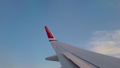 POV-Aus-Dem-Fenster-Neben-Dem-Flügel-Eines-Norwegischen-Flugzeugs,-Das-Hoch-Am-Himmel-Steht