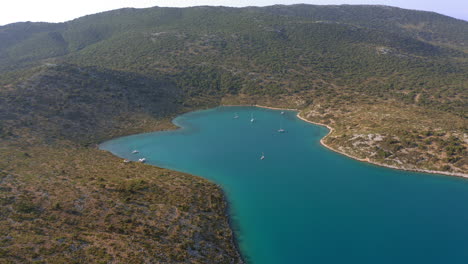 Aerial:-Slow-panning-drone-shot-of-planitis-bay-of-the-island-of-Kira-Panagia-in-Sporades,-Greece-with-amazing-turquoise-and-emerald-crystal-clear-water