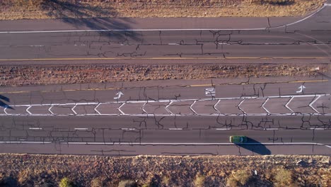 Top-Down-Aerial-View,-Traffic-on-American-Desert-Road,-State-Route-With-Vehicles-and-Cracked-Asphalt,-High-Angle-Drone-Shot