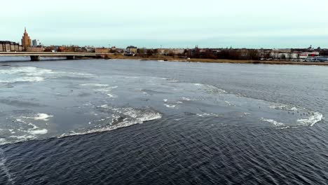 Ein-Zugefrorener-Fluss-Mit-Einer-Brücke-Im-Hintergrund