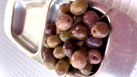 Vertical-close-up-view-of-olives-in-a-silver-scale