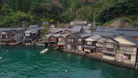 Aerial-Drone-panoramic-of-stilt-traditional-Japanese-houses-near-sea-coastline-in-kyoto-beach,-Kyotango-seascape-with-birds-and-Asian-atmosphere-by,-wooden-homes,-Travel-destination