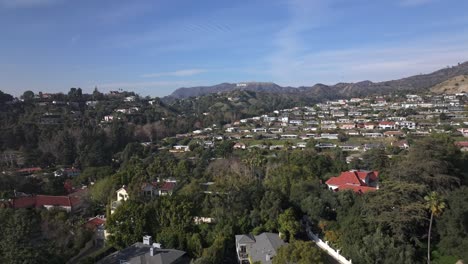 Neighborhood-of-homes-on-clear-day-in-Los-Angeles,-Hollywood-sign-in-distance,-aerial-view