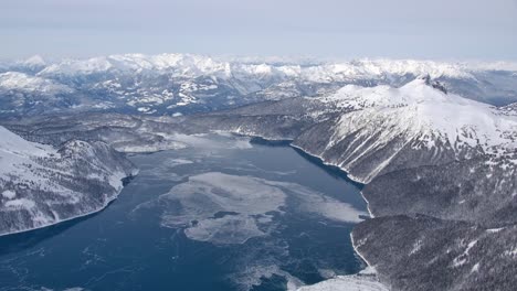 Icy-Mountain-Lake-on-a-Bleak-Winter-Day-High-Aerial-View-from-Airplane