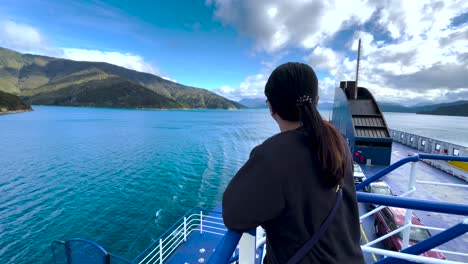 Frau-Mit-Schwarzem-Pferdeschwanz-Auf-Der-Bluebridge-Fähre-Mit-Blick-Auf-Wasser,-Hügel-Und-Wolken-Im-Queen-Charlotte-Sound