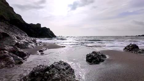 Corriente-En-Cámara-Lenta-Que-Fluye-Hacia-El-Mar-En-Una-Playa-Rocosa-En-Waterford,-Irlanda