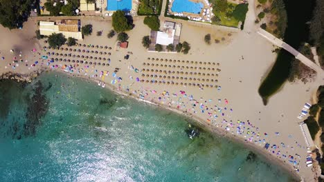 Orbiting-drone-shot-above-the-beachfront-of-Playa-de-Canyamel,-located-in-the-island-of-Mallorca,-off-the-coast-of-Spain-in-the-Mediterranean-Sea