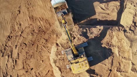 Yarrawonga,-Victoria,-Australia---8-March-2024:-Rising-up-top-down-view-of-an-excavator-loading-a-tip-truck-with-dirt-at-Silverwoods-Estate-in-Yarrawonga