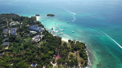 Epic-aerial-view-descending-and-tilting-the-camera-on-a-Caribbean-touristic-island-with-boats-and-buildings,-Dominican-Republic