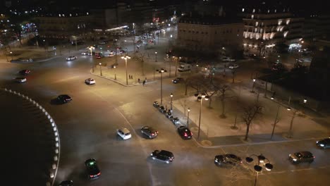 Cars-driving-at-night-along-roundabout-in-Paris-city-center,-France