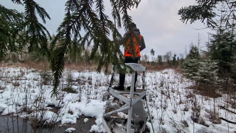 Hunter-surveys-the-hunting-area-in-winter,-his-rifle-slung-over-his-shoulder
