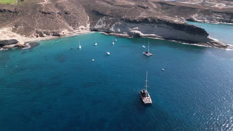 people-bathing,-catamaran-in-blue-sea-water,-beautiful-bay-on-an-island,-tenerife,-boat,-summer,-drone