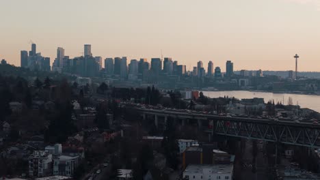 Der-Verkehr-Fließt-In-Der-Goldenen-Abendstunde-über-Eine-Brücke-Mit-Der-Skyline-Der-Innenstadt-Von-Seattle-Und-Der-Space-Needle-Am-Lake-Union-Im-Hintergrund