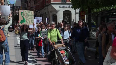 Woman-with-dinosaur-sign-at-climate-protest-march-in-Stockholm,-slomo