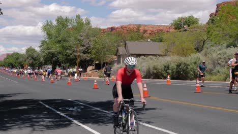 Slow-motion-shot-of-cyclist-in-red-shirt-and-runners-at-the-Intermountain-Health-IRONMAN-70