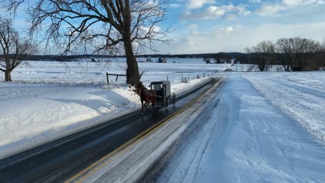 Car-passing-Amish-buggy-on-snowy-road-in-Lancaster-County,-Pennsylvania