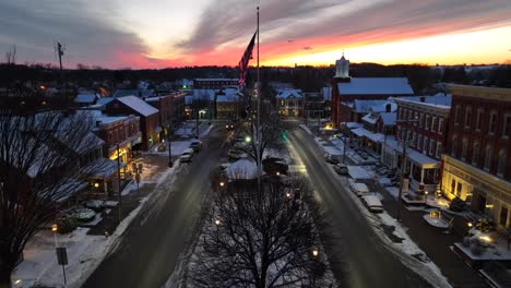 American-flag-waving-in-town-square-during-colorful-sunset-on-snowy-winter-evening