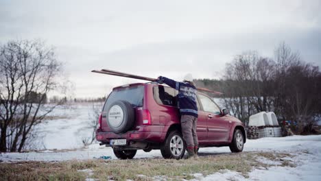 The-Man-is-Placing-Several-Planks-of-Wood-Onto-the-Roof-of-His-Car-in-Indre-Fosen,-Trondelag-County,-Norway---Timelapse