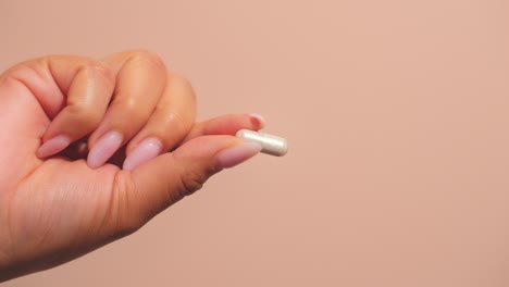 Female-hand-holds-a-capsule-or-pill,-symbolizing-wellness
