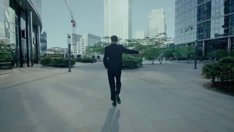 Confident-Business-Man-In-Suit-Walking-and-Greeting-Outdoors-At-Financial-District,-Back-Tracking-View