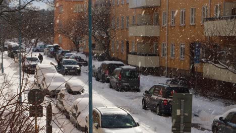 Snow-falls-on-cars-and-people-on-street-in-winter-in-Stockholm,-Sweden